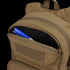 The Condor Fuel Hydration Backpack 18L in tan features a partially open zippered pocket, revealing a blue and white pen and black marker—ideal for organized gear storage on the move.